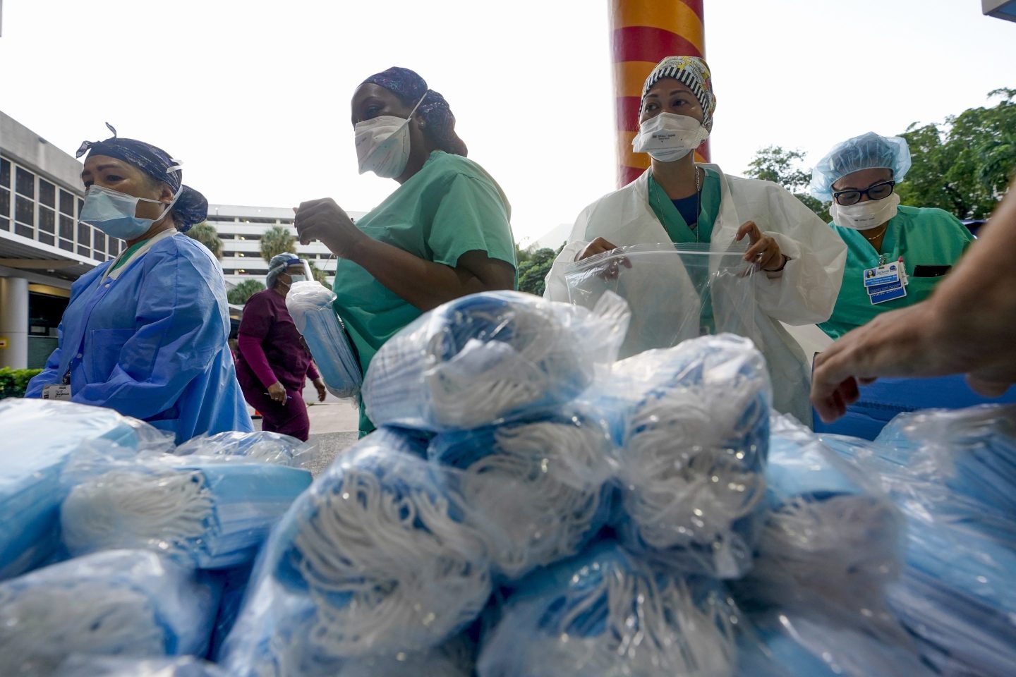 FILE &#8211; Healthcare workers line up for free personal protective equipment in front of murals by artist Romero Britto at Jackson Memorial Hospital, Tuesday, Sept. 22, 2020, in Miami. Some states that stockpiled millions of masks and other personal protective equipment during the coronavirus pandemic are now throwing the items away.(AP Photo/Wilfredo Lee, File)