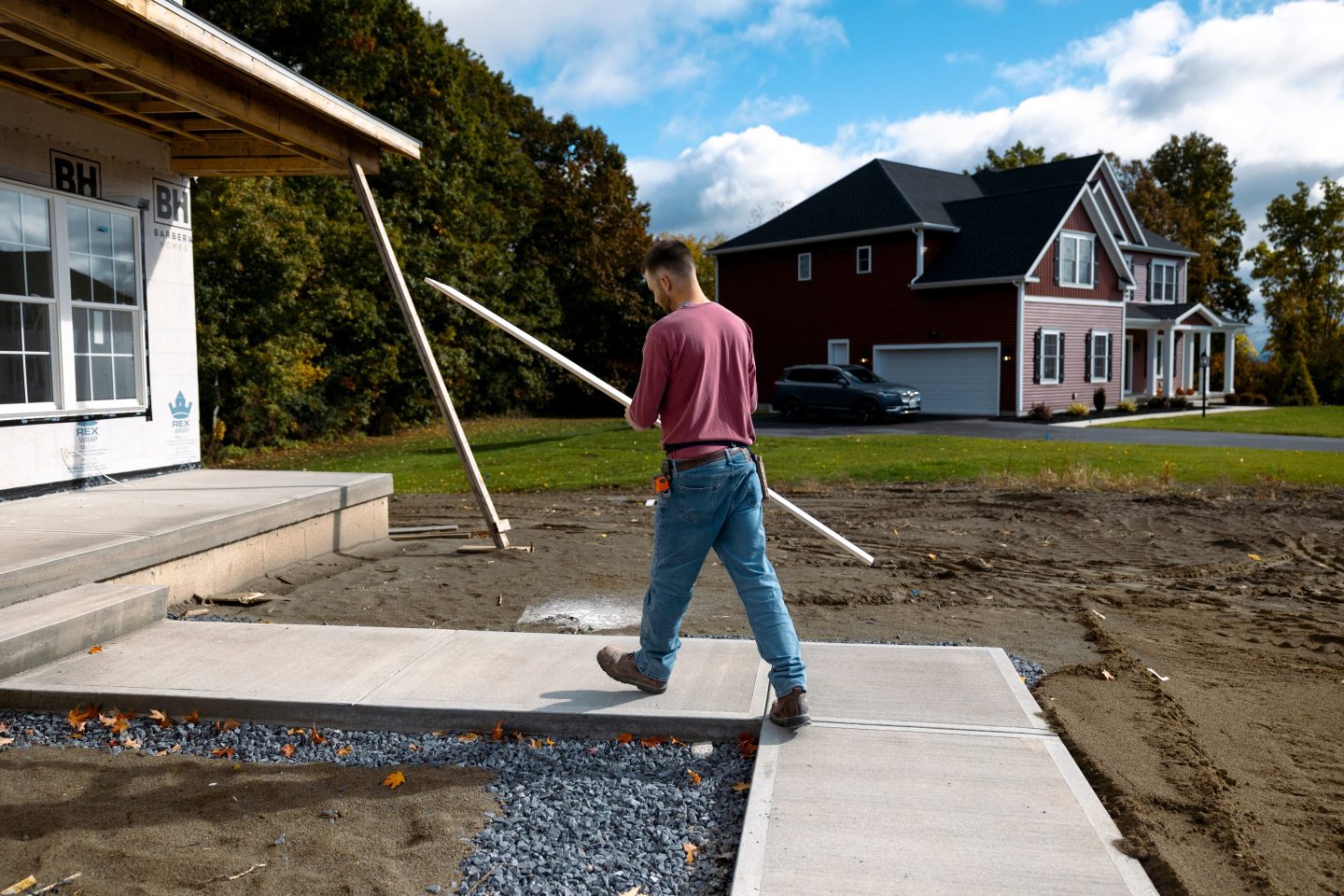 A worker carries a piece of trim into a home under construction