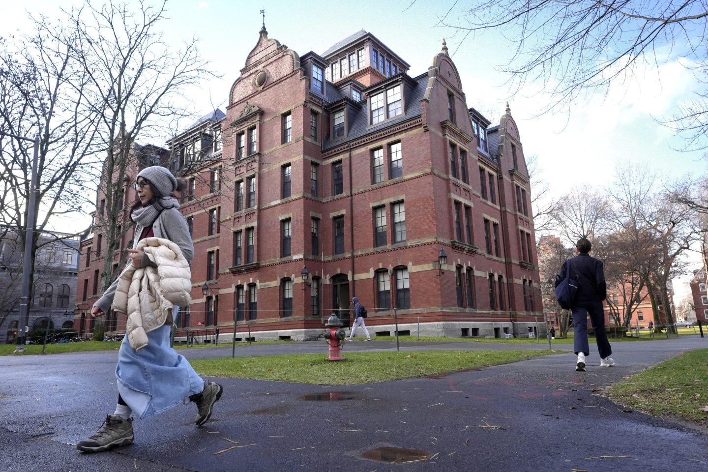 FILE &#8211; People walk between buildings, Dec. 17, 2024, on the campus of Harvard University in Cambridge, Mass. (AP Photo/Steven Senne, File)