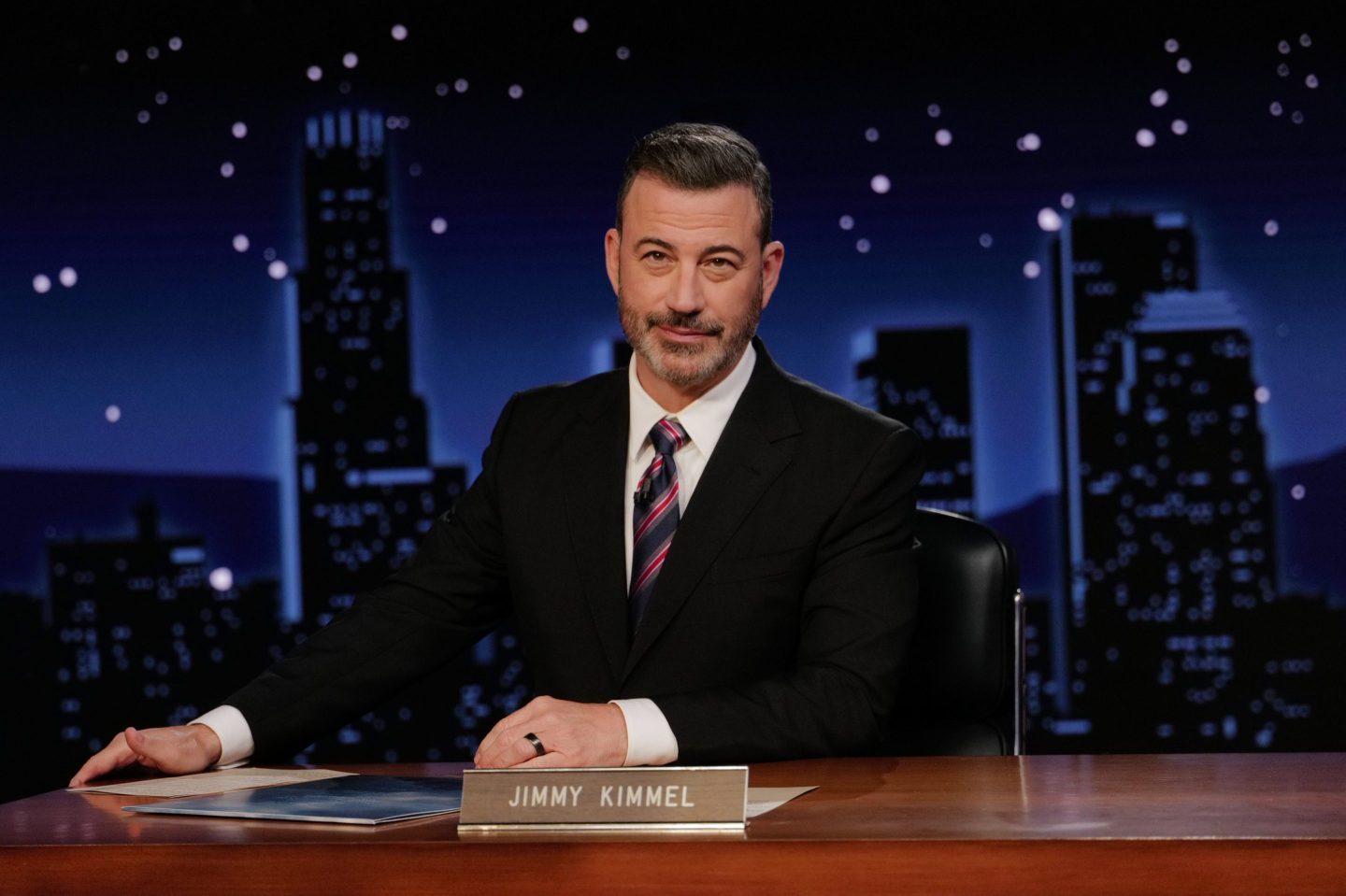 Jimmy Kimmel sits at his desk on set