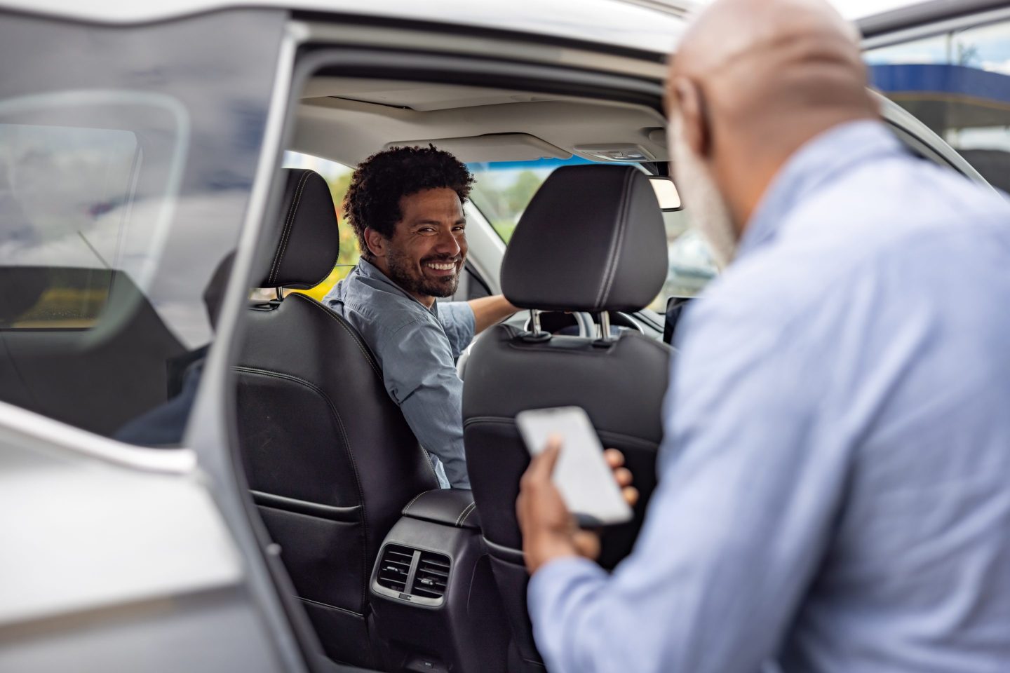 African American crowdsourced taxi driver picking up a passenger and smiling &#8211; mobility as a service concepts